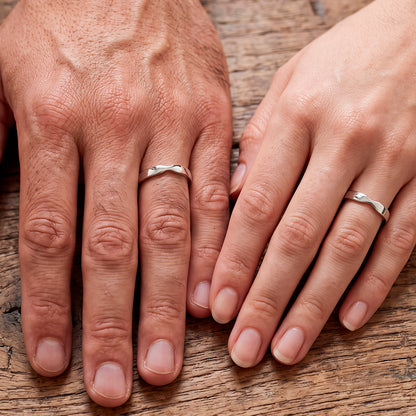 Mãos de um casal usando as alianças de namoro Belle em prata 925
